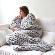 a woman wrapped in a blanket sitting on a couch