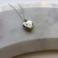 Vintage silver heart pendant on chain.This vintage silver heart shaped pendant features engraving on the front with a plain back. There are also the initials 'FJW' engraved on the top corner of the pendant. There is a small dent near the edge on the back (see photograph). Comes on a modern sterling silver 18" chain or with no chain, please select which from the dropdown box.Marked 'SILVER' on the reverse.Locket measures 1.5cm wide, 1.6cm high, 0.5cm deep.The necklace will come beautifully presen Vintage Sterling Silver Heart Charm Necklace, Vintage Double Heart Engraved Necklace, Valentine's Day Silver Etched Necklace, Silver Etched Necklace For Valentine's Day, Vintage Heart Charm Necklace Engraved, Silver Sterling Heart Necklace For Memorial, Silver Heart Pendant Locket Necklace, Silver Heart-shaped Etched Necklace, Silver Heart Charm Locket Necklace