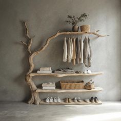 a wooden shelf with shoes and clothes on it next to a tree branch that is leaning against the wall