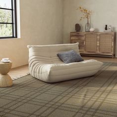 a living room filled with furniture and a rug on top of a wooden floor next to a window