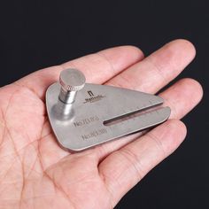 a hand holding a small metal object in it's palm