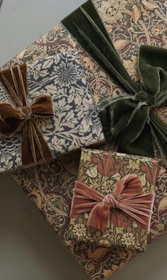 three wrapped gift boxes with bows tied on top of each other in various patterns and colors