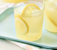 two glasses filled with lemonade sitting on top of a blue tray