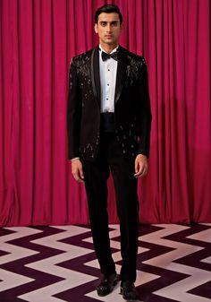 Step into elegance with our Black Textured Tuxedo Set. Crafted from luxurious textured suiting, this set features an elegant black blazer embellished with intricate linear embroidery. Paired with an embellished bowtie, sash, pintuck shirt, and pants, it's the ideal choice for cocktails or wedding receptions. Make a statement and exude sophistication in this stunning tuxedo set. Components : 5 (Blazer, Shirt, Bowtie, Sash and Pants) Composition : Textured Suiting Care: Dry Clean Only and Vacuum Storage This product can be customized for sleeves, length of blouse and neckline Delivery : 4-6 weeks as the product is hand crafted. Check Size Guide or choose MySize for free customisation (All Sizes above XL can be made at 15% additional cost) For more information and sizes please contact fabilic Embellished Notch Lapel Suits For Semi-formal Occasions, Tailored Party Wear Blazer For Semi-formal Occasions, Elegant Tuxedo For Black-tie Festive Events, Designer Fitted Bandhgala For Evening, Tailored Tuxedo Sets For Gala, Fitted Blazer For Black-tie Festive Events, Festive Fitted Blazer For Black-tie Events, Elegant Tuxedo For Gala And Festive Occasions, Luxury Festive Tuxedo For Gala