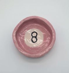 a pink bowl with the number eight in it's center, on a white background