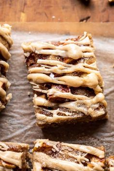 several pieces of dessert sitting on top of a piece of wax paper next to nuts