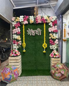 an arrangement of flowers and garlands on display in front of a green backdrop with the word india