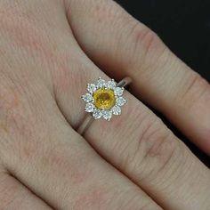 Yellow Sapphire Ring Flower Halo Diamond Blossom Petal Motif Plain Delicate Modern Floral Engagement Ring Subtle and romantic engagement ring made of 14K white gold (Platinum also available). Features one round yellow sapphire center stone (5mm, ~.70ct) surrounded by a flower shaped halo made up of diamonds (.35cttw, G-SI1 quality) set in prongs. Dimensions: 2mm wide, 1.1mm high (shank), center stone sits 7mm above finger, weight: 2.8g (taken from a size 7.5) This ring can be made with a variety Luxury Flower Ring With Halo Setting For Wedding, White Gold Flower Ring With Halo Setting For Wedding, Fine Jewelry Flower Ring With Halo Design, Fine Jewelry Flower Cluster Ring With Gemstone, Elegant Yellow Flower-shaped Ring, Luxury Flower Ring With Halo Setting For Promise, Yellow Diamond Halo Ring For Wedding, Floral Cluster Ring With Halo Setting For Wedding, Flower Shaped Cluster Ring With Halo Setting For Wedding