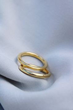 two gold rings sitting on top of a white cloth