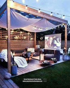 an outdoor movie theater is set up in the backyard with string lights strung around it