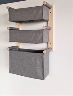 two grey storage bins hanging on the side of a white wall with wooden handles