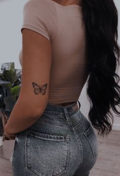 a woman with a butterfly tattoo on her left arm and right hand behind her back