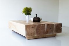 a wooden table with two vases on it and one plant sitting on top of it