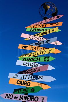 a pole with many different colored street signs attached to it's sides in front of a blue sky