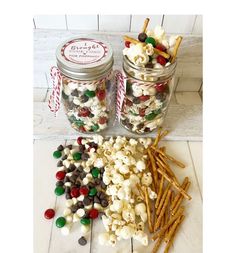 two jars filled with candy and marshmallows on top of a white tile floor