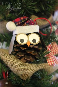 an owl ornament is sitting on top of a christmas tree with pine cones