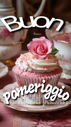 there is a cupcake on the plate with a pink rose on top that says buon ponerigio