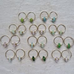 a bunch of small rings with different colored beads on each one side and gold filled hoop earrings in the middle