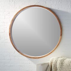 a round mirror hanging on the side of a white brick wall