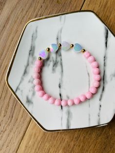 a pink beaded bracelet on a marble tray