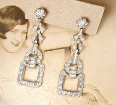 "Offering a gorgeous pair of authentic vintage, circa 1920s - 1930s era, Art Deco long clear French paste crystal rhinestone Flapper pendant dangle earrings. The perfect \"Something Old\" for the Bride and with a pair of jeans and a tee after!  The ornate SO 1920s long geometric flapper silver pot metal earrings feature baguette cut clear sparkly crystal rhinestone accents while the rest is lavishly encrusted with pave set small round cut sparkly clear crystal rhinestones.  The earrings are made Vintage Chandelier Dangle Earrings For Anniversary, Vintage Dangle Chandelier Earrings For Anniversary, Elegant Vintage Charm Earrings For Wedding, Elegant Vintage Charm Wedding Earrings, Vintage Dangle Bridal Earrings For Anniversary, Vintage Chandelier Earrings For Formal Occasions, Vintage Dangle Bridal Earrings, Retro Wedding Jewelry With Matching Earrings, Vintage Bridal Earrings For Evening