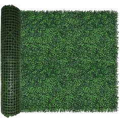 a roll of green grass next to a tall piece of black wire fence on top of a white background