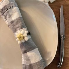 a white plate topped with a flower next to a knife and fork