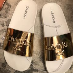 Some Nice Calvin Klein Slides To Wear Out And About Or Inside The House. Size 6m, Fits Up To A Womens 7.5 Without Socks. Unisex, Item Is New With Tags Casual Gold Flip Flops With Flat Heel, Casual Gold Flat Heel Flip Flops, Gold Open Toe Synthetic Slides, Gold Slippers For Summer, Gold Open Toe Slides, Gold Synthetic Open Toe Slides, Gold Round Toe Slides For Spring, Gold Round Toe Slides For Beach, Gold Synthetic Slide Sandals