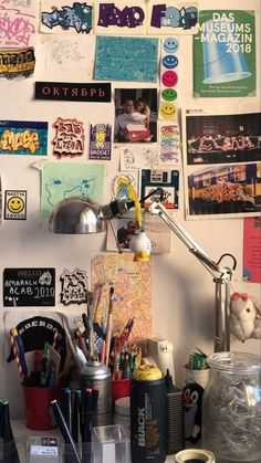 a cluttered desk with many different items on the wall and pictures all over it