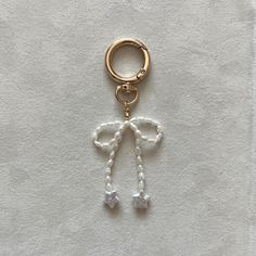 a keychain with a bow and beads hanging from it's side on a white surface