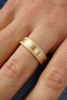 a close up of a person's hand with a gold ring on their finger