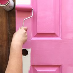 a person painting a pink door with a paint roller