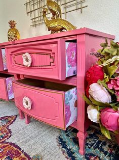 a pink dresser sitting on top of a rug next to a vase filled with flowers