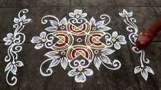 a person standing next to a white and red flower design on the ground with one hand