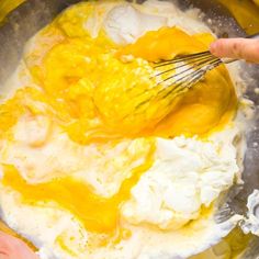 two hands whisk eggs in a mixing bowl