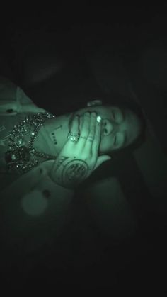 a woman with tattoos and piercings on her head is laying down in the dark