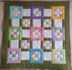 a quilted wall hanging on the side of a building with colorful squares in it