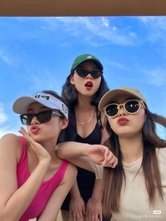 three young women wearing sunglasses and hats posing for the camera with their arms around each other