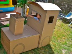 a little boy is playing in a cardboard box house with his hands on the window