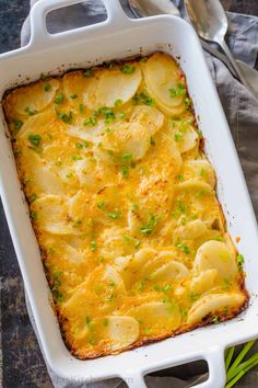 a casserole dish with potatoes and green onions in it on top of a table