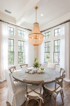 a dining room table with chairs and a chandelier hanging from it's ceiling