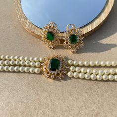 Inspired by Princess Diana's timeless grace, adorn yourself in the regal elegance of the SapphireArtTreasure Pearl Emerald Choker. This gorgeous necklace perfectly combines eye-catching emerald green stones with glossy pearls accented with American diamonds. It adds a touch of elegance and celebrates the rich legacy of Indian jewellery artistry, making it ideal for bridal ceremonies. On your special day, make a sophisticated and beautiful statement by living up to the royal charm. *𝐏𝐑𝐎𝐃𝐔𝐂𝐓 𝐃𝐄𝐓𝐀𝐈𝐋* * Material: Brass * Plating: White Rhodium Plated * Stone: AAA-quality CZ diamond, Emerald & Pearls. *𝐃𝐈𝐌𝐄𝐍𝐒𝐈𝐎𝐍𝐒*  Necklace * Weight: 32 gm * Length: 11 Inches * Width: 1.25 Inches  Earrings * Weight: 8 gm each * Length: 1.25 Inches * Width:  1 Inches * Closure: Push Back * Luxury Green Stone Work Sets, Luxury Green Temple Jewelry Choker, Luxury Green Kundan Necklace For Ceremonial Occasion, Elegant Emerald Necklace With Jewels For Party, Elegant Emerald Necklace For Party, Formal Green Pearl Necklaces, Elegant Green Bridal Necklace For Formal Occasions, Elegant Emerald Gemstone Necklace For Party, Elegant Emerald Bridal Necklace