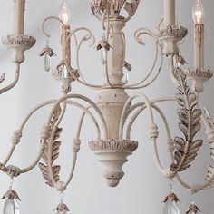 a white chandelier with crystal drops hanging from it's arms and two candles in the center