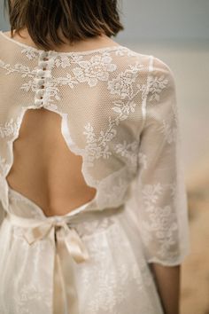 the back of a woman's wedding dress with an open back and lace detailing