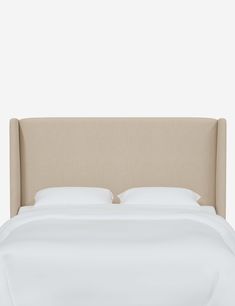 an upholstered headboard with white sheets and pillows on top of a bed