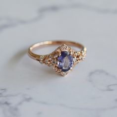 a gold ring with a tan sapphire and diamond accents on the side, sitting on a marble surface