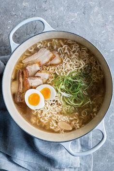 a bowl of ramen with meat, noodles and an egg on the side next to a spoon