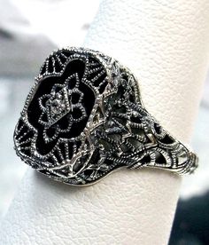 Black Camphor Glass & White Gem Ring  Cathedral Design#204 Custom Made This is a lovely detailed and intricate Art Deco reproduction ring. This lovely filigree reproduction ring is handcrafted in sterling silver. The lovely black glass camphor stone is 11mm x 9mm. The face of the ring is 13.5mm North South and 10mm East West on the finger. Notice the 1mm center white gemstone; choose White CZ, Lab Moissanite, or Natural Diamond.  The inside of the band is marked 925 for sterling silver. This is Art Deco Filigree, Antique Filigree, Gemstone Art, Glass Ring, Gem Ring, Glass Rings, Antique Design, Filigree Ring, Engraved Items