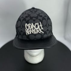 a black coach hat with the word coach on it sitting on top of a white mannequin head