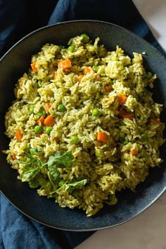 a bowl filled with rice and vegetables on top of a blue cloth next to a fork